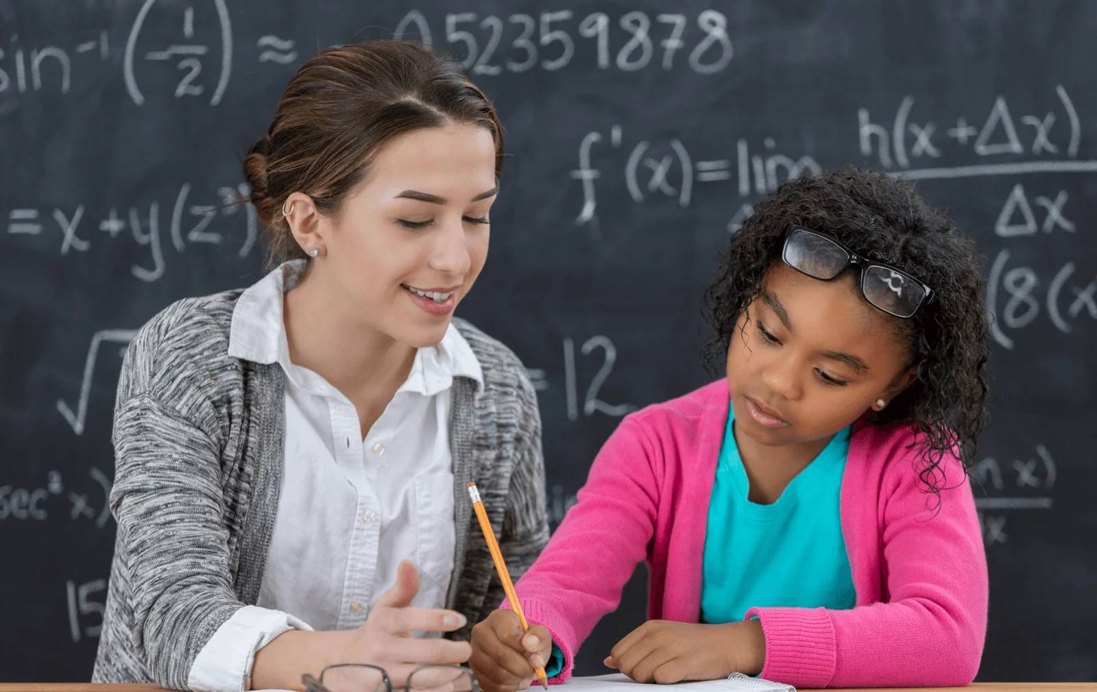 Math tutoring session with teacher helping student at blackboard